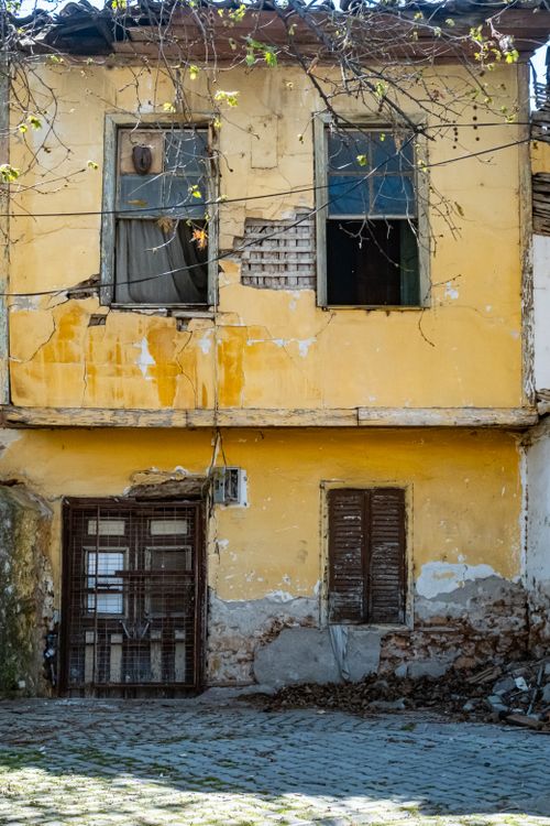 Free An aged, yellow building with rustic windows and visible decay, perfect for themes of urban exploration. Stock Photo