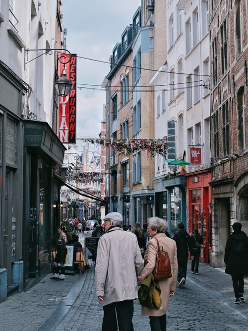 Free A bustling street in Brussels with pedestrians exploring shops and restaurants. Stock Photo