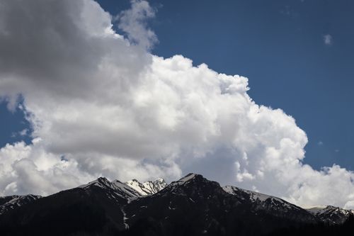 Free Majestic snow-capped mountains with a dramatic cloudy sky in the background, perfect for nature enthusiasts. Stock Photo