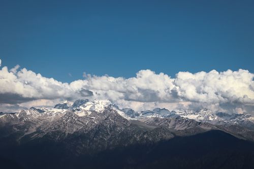 Free Snow-capped peaks of the Himalayan mountains under a clear blue sky with fluffy clouds. Stock Photo