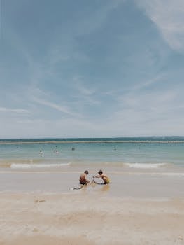 Two children playing on a serene beach in Brazil under a clear blue sky.