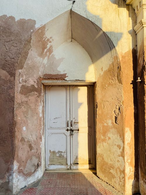 Free Sunlit weathered archway and door, capturing rustic textures in Patiala, India. Stock Photo