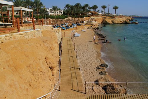 Free Sunny beach with wooden walkway and lounge chairs on a beautiful day. Stock Photo