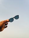 Low angle of faceless tourist showing modern black shades on background of sky at dusk