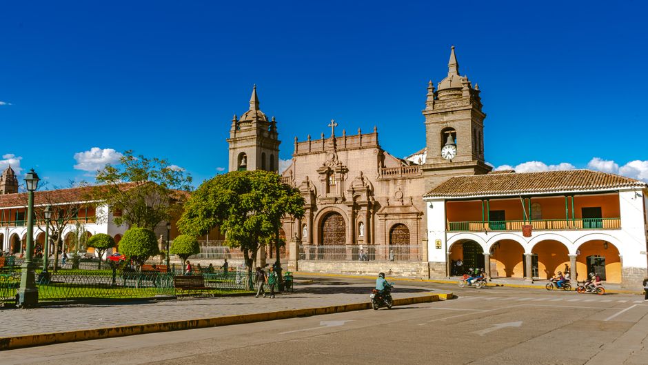 Historic colonial architecture in Sucre's main city square, Bolivia, under a bright blue sky.
