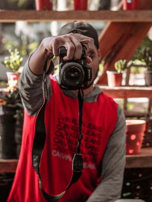 Free Man in Red Shirt Holding Black Nikon Dslr Camera Stock Photo
