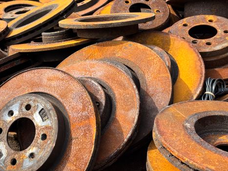 Close-up of rusty car brake discs stacked outdoors, capturing texture and patina.