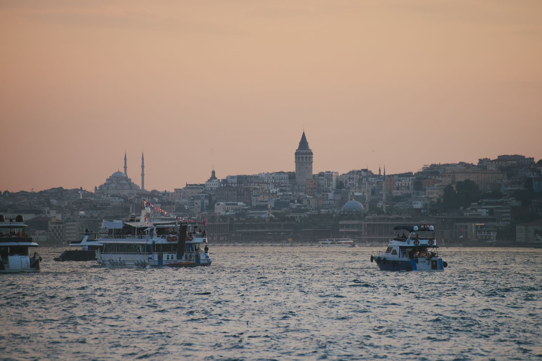 Captivating view of Istanbul at sunset, featuring the iconic Galata Tower and boats on the Bosphorus.