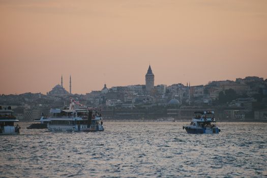 Captivating view of Istanbul at sunset, featuring the iconic Galata Tower and boats on the Bosphorus.