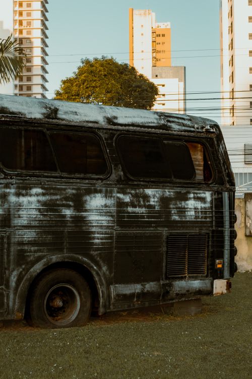 Free An old, weathered bus sits amidst the urban landscape of Natal, Brazil, with a sunset glow. Stock Photo