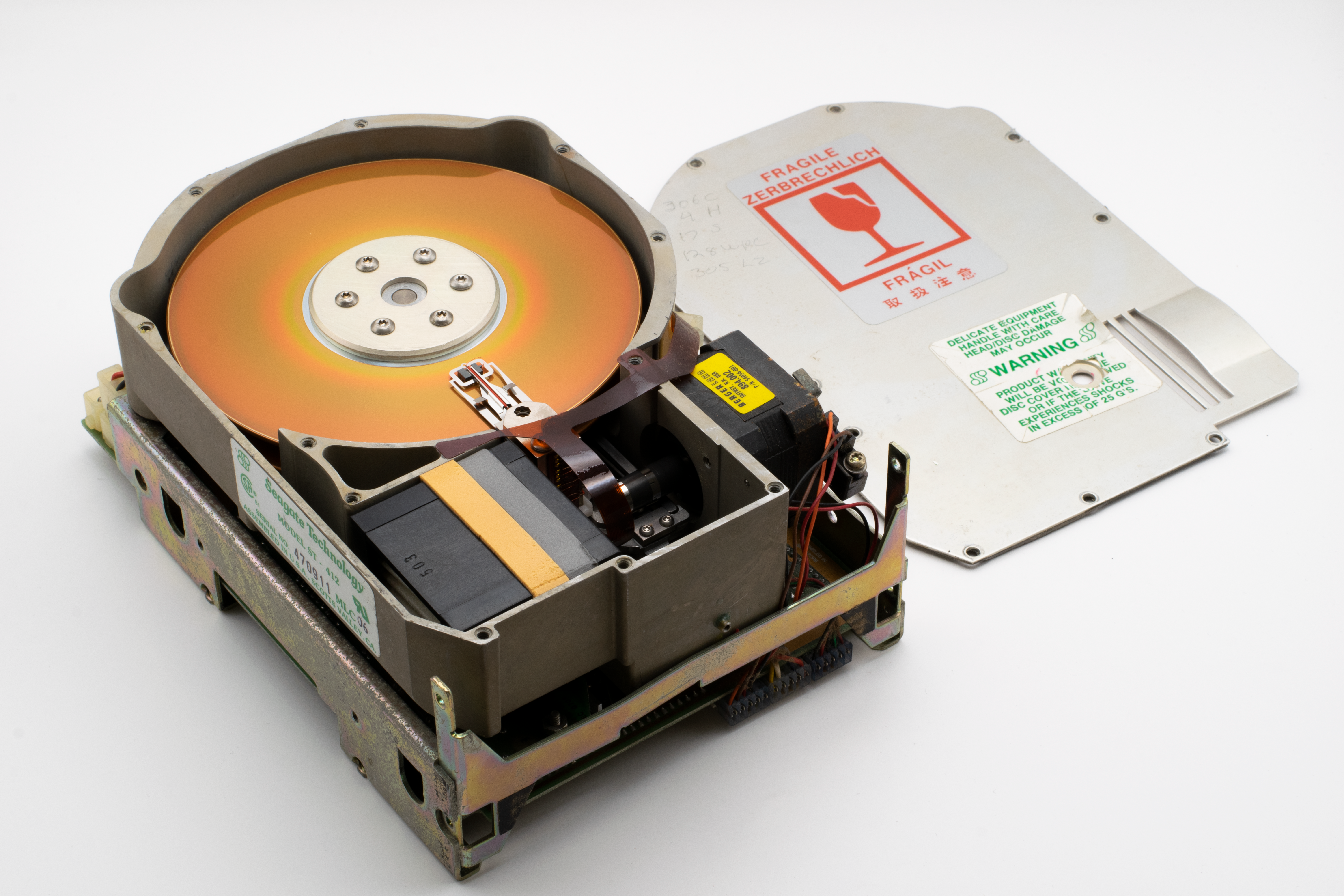 Exposed vintage hard drive showing disk platter and internal components, highlighting historical technology.