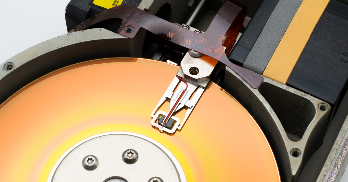 Detailed view of a vintage hard disk drive showing the read/write head and spinning platter.