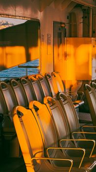 Sunlit ferry seats in İzmir, Türkiye, capture the golden glow of dusk, providing a serene travel moment.