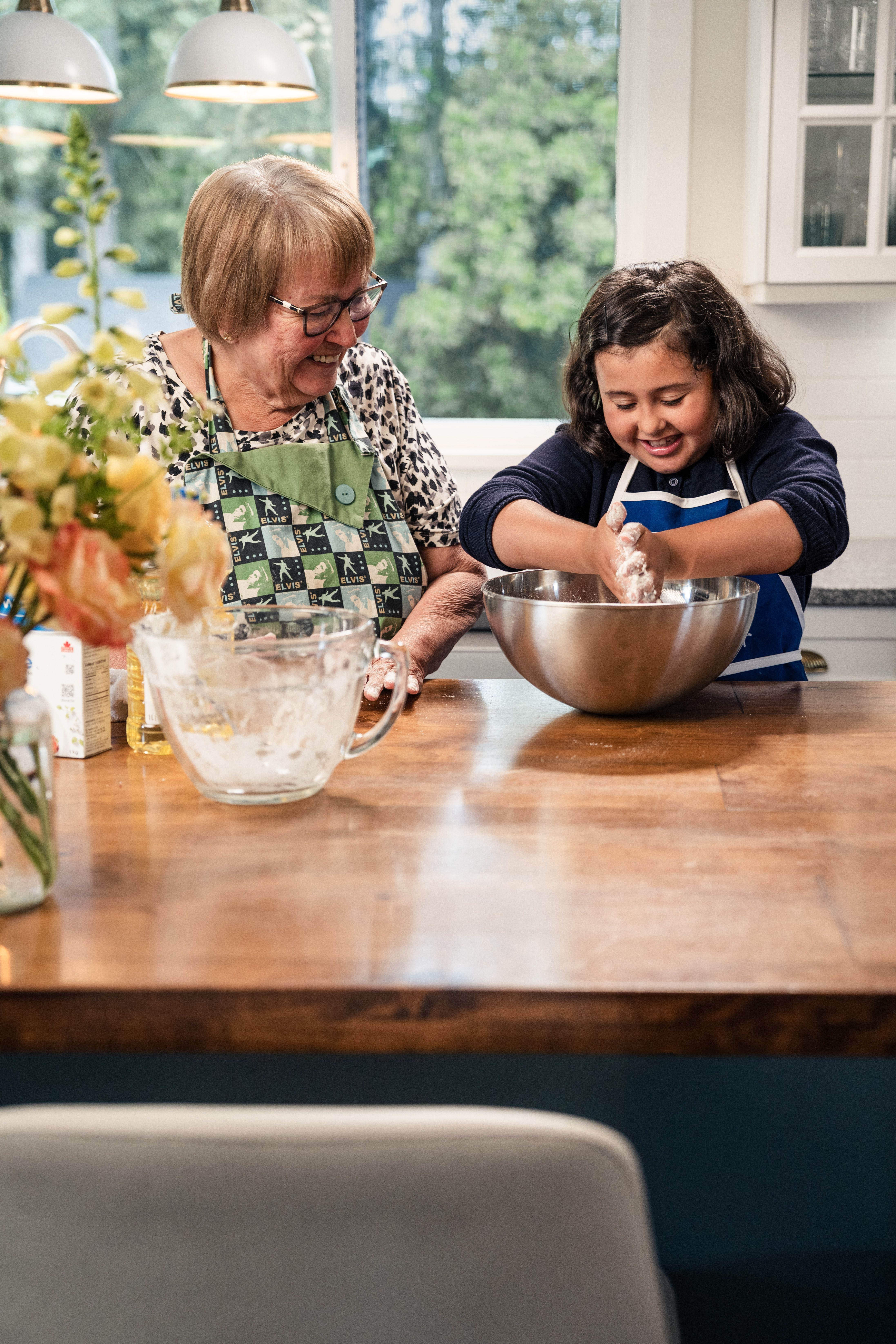 Cheerful grandmother and granddaughter bonding while baking in a cozy kitchen.
