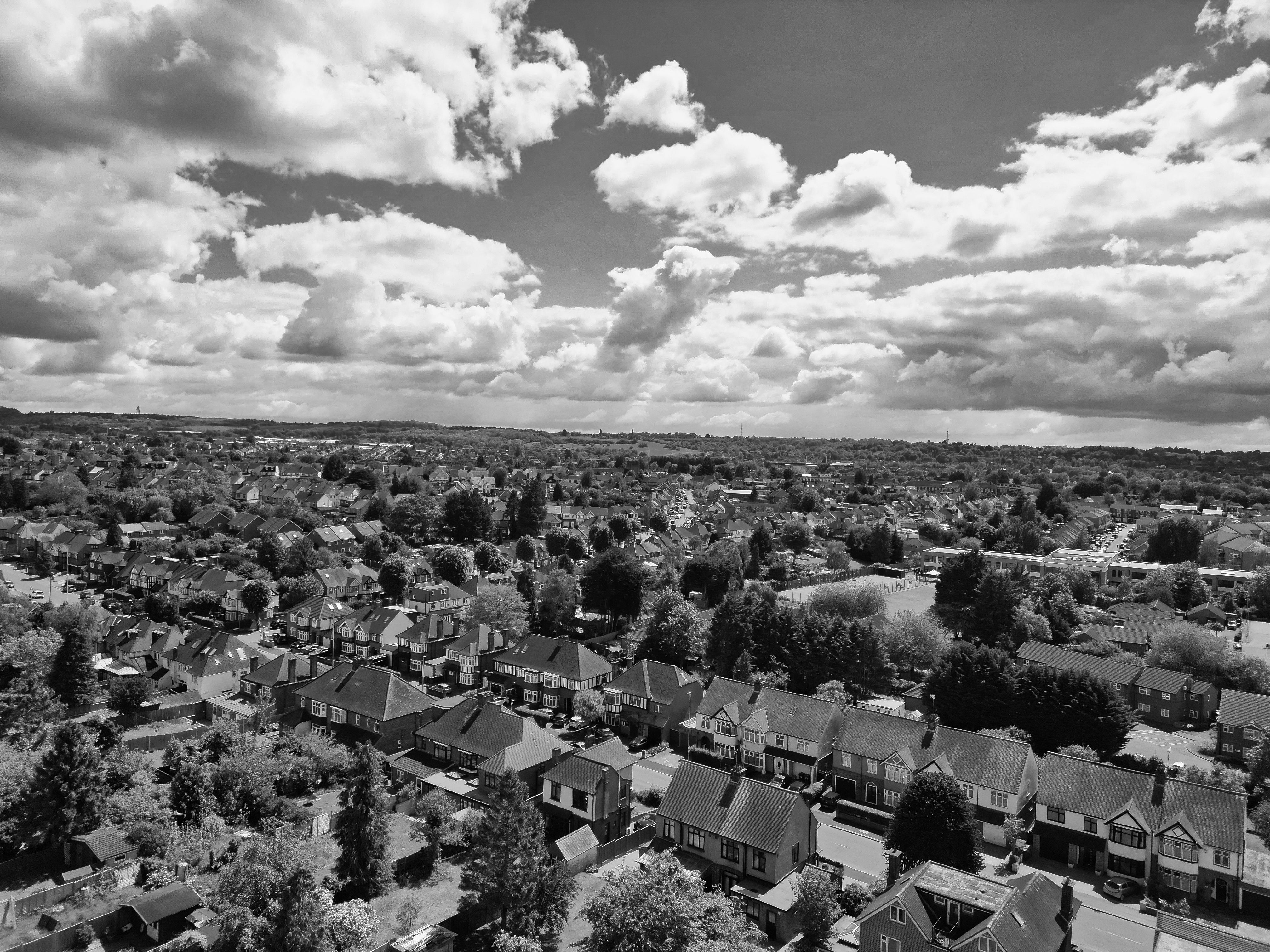 Black and white aerial photo capturing a picturesque British suburb under a cloudy sky.