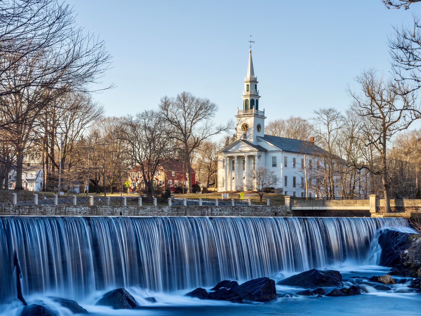 Peaceful landscape with a flowing waterfall and historic church in Milford, CT.