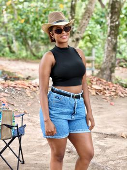 Young woman in casual summer clothing smiling outdoors, enjoying a day in nature.