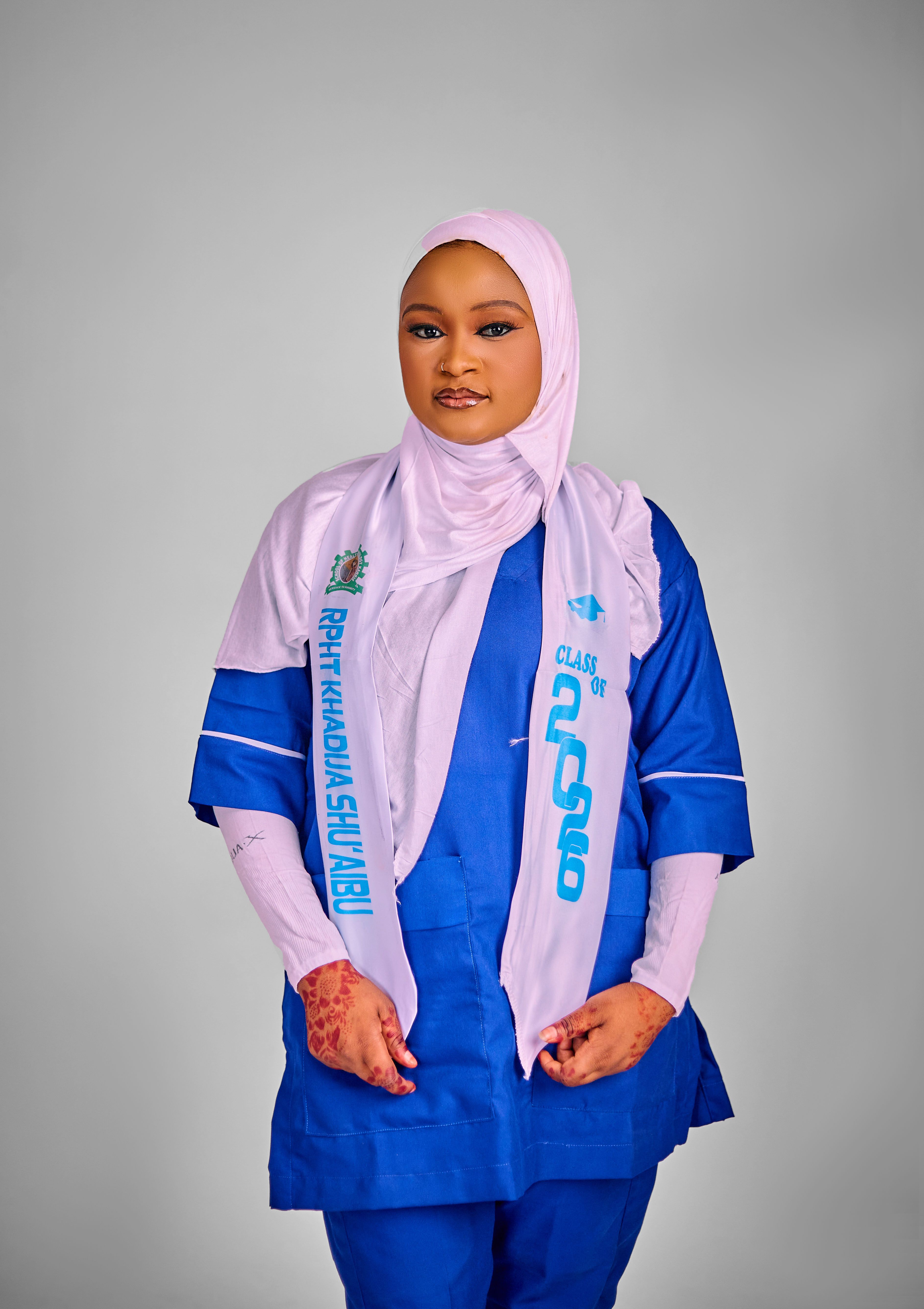 Young woman in graduation attire with traditional henna designs, posing confidently.