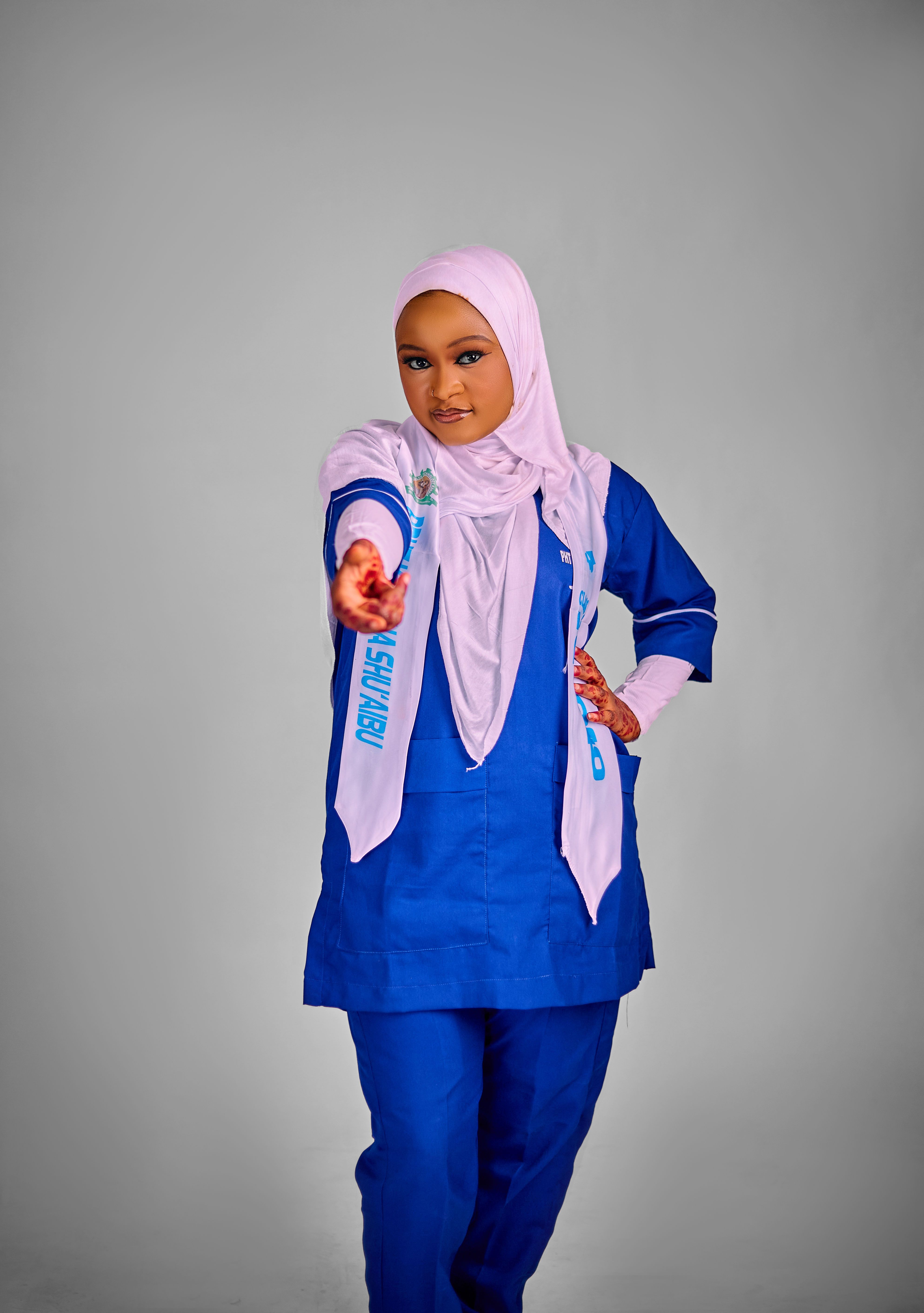 Confident woman in blue uniform and hijab gesturing forward.