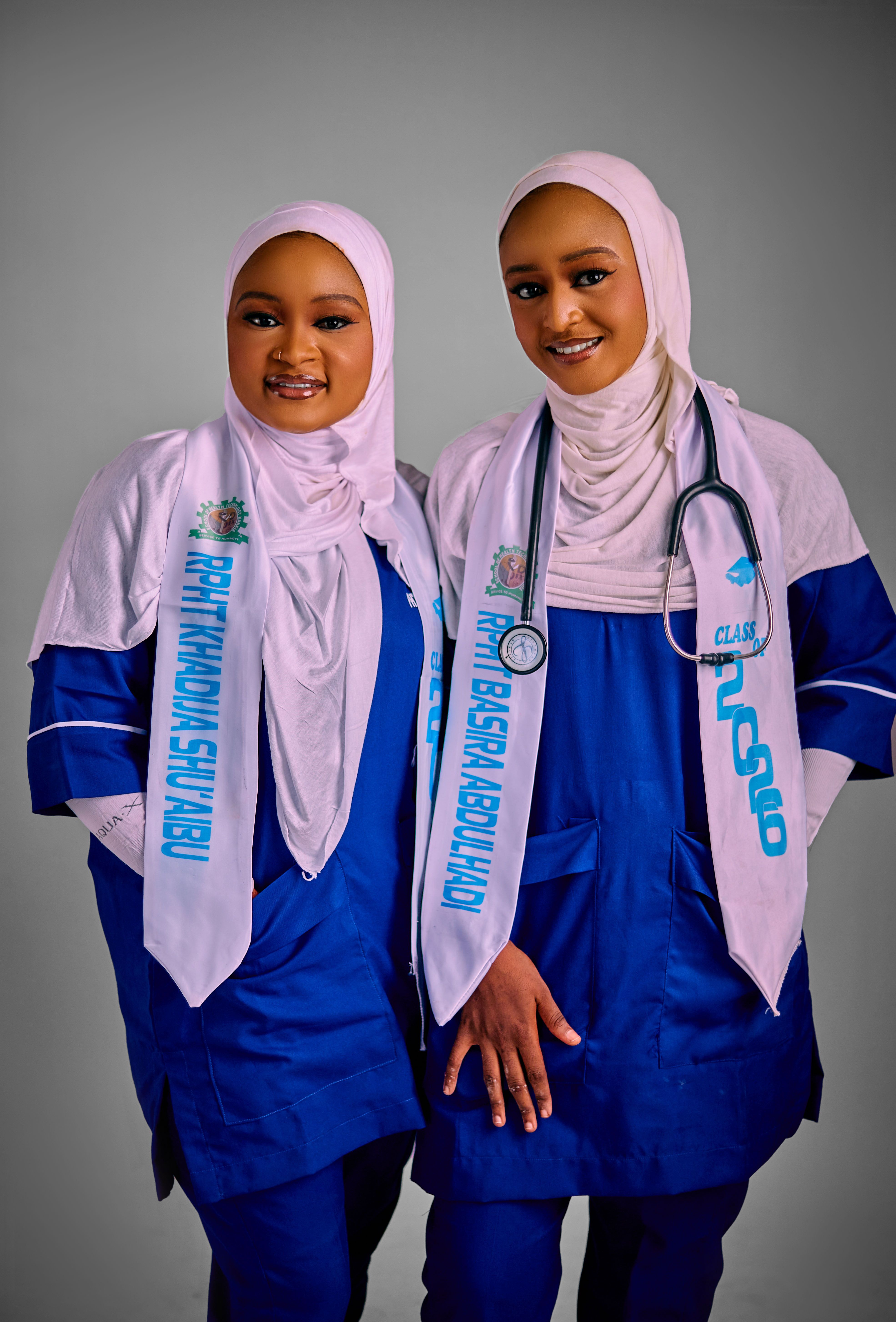 Two young female medical graduates wearing hijabs and stethoscopes.