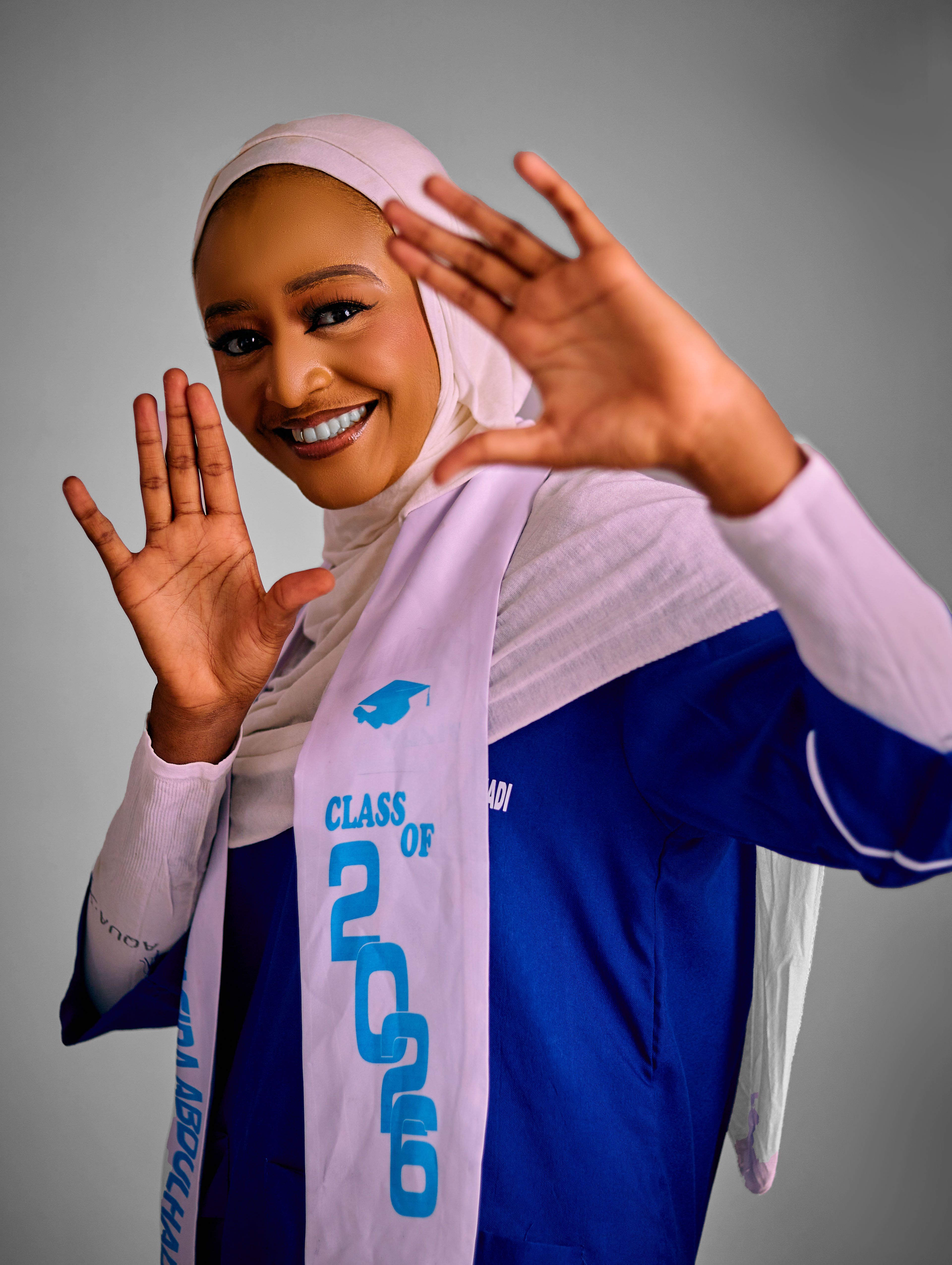 Young woman celebrating her 2026 graduation with a bright smile and open arms.