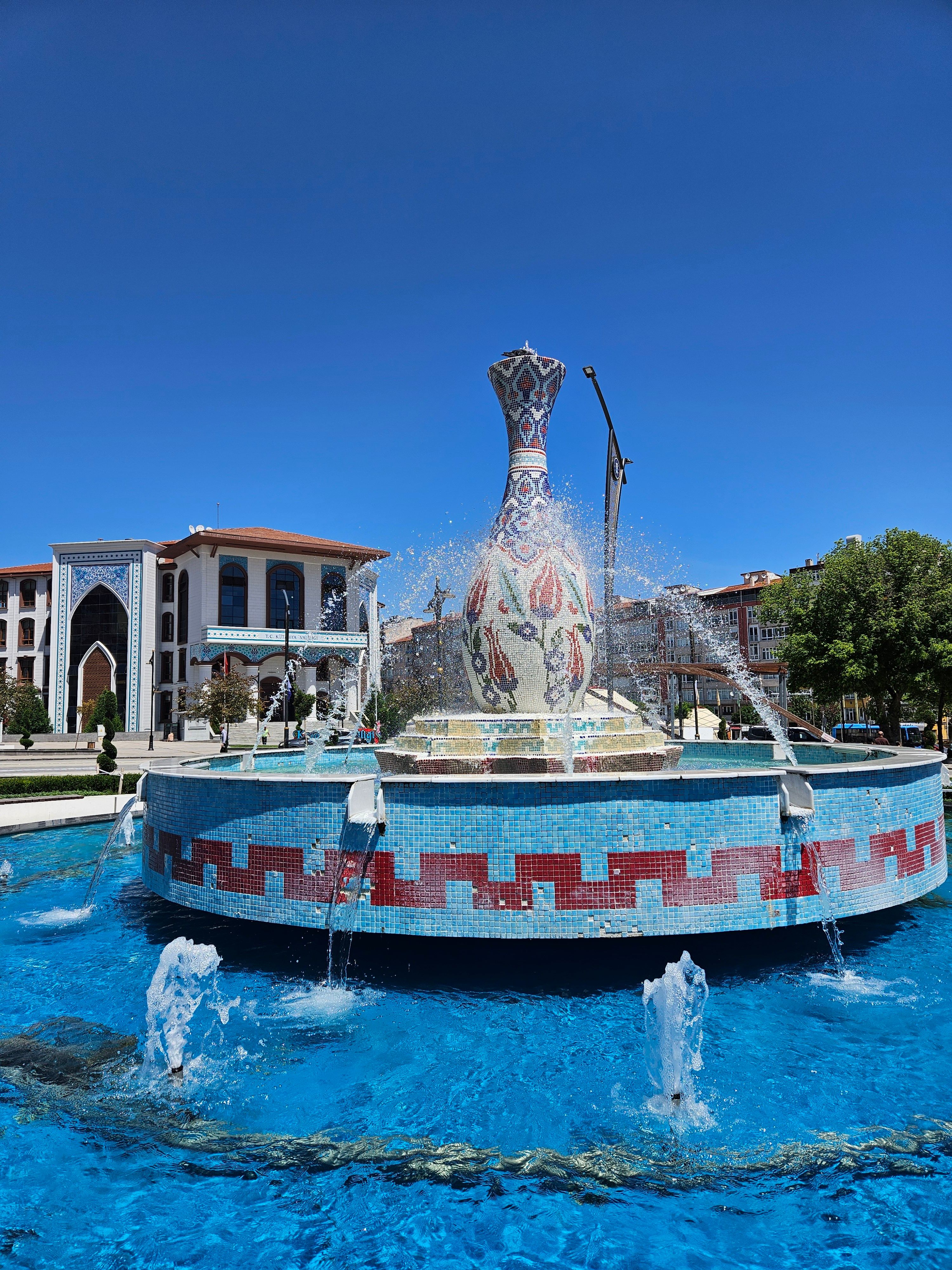 Vibrant fountain with traditional motifs in a sunny city square.