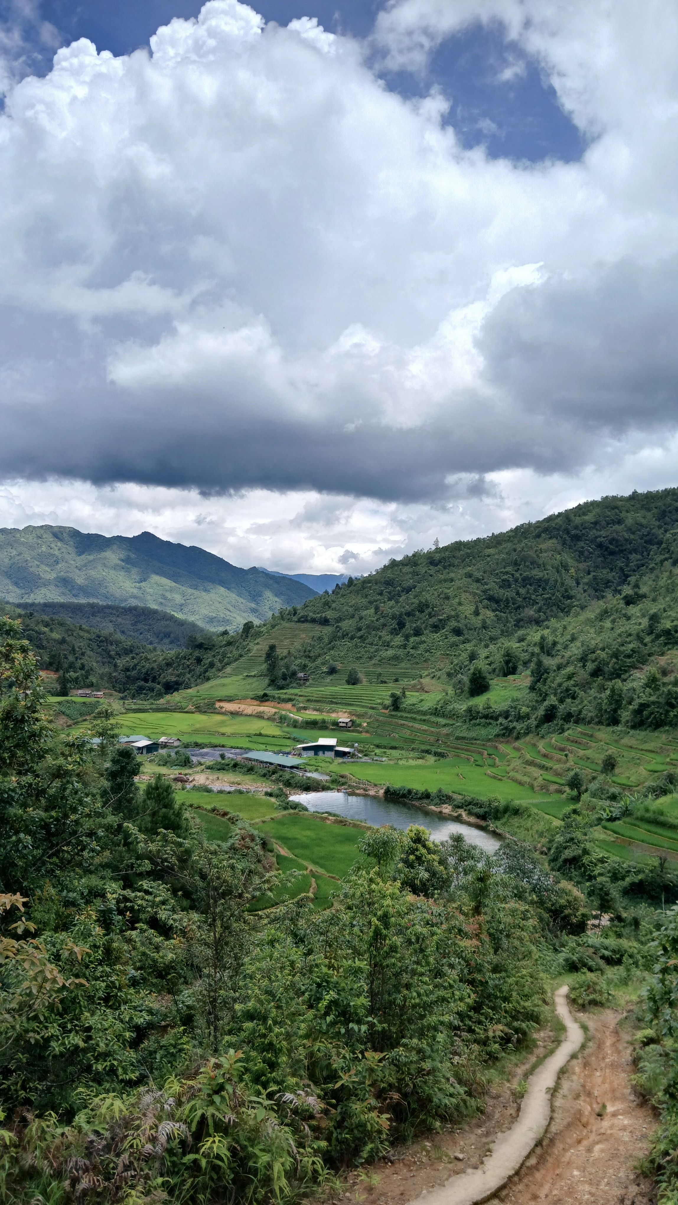 Picturesque view of a lush green valley with a river under dramatic clouds.