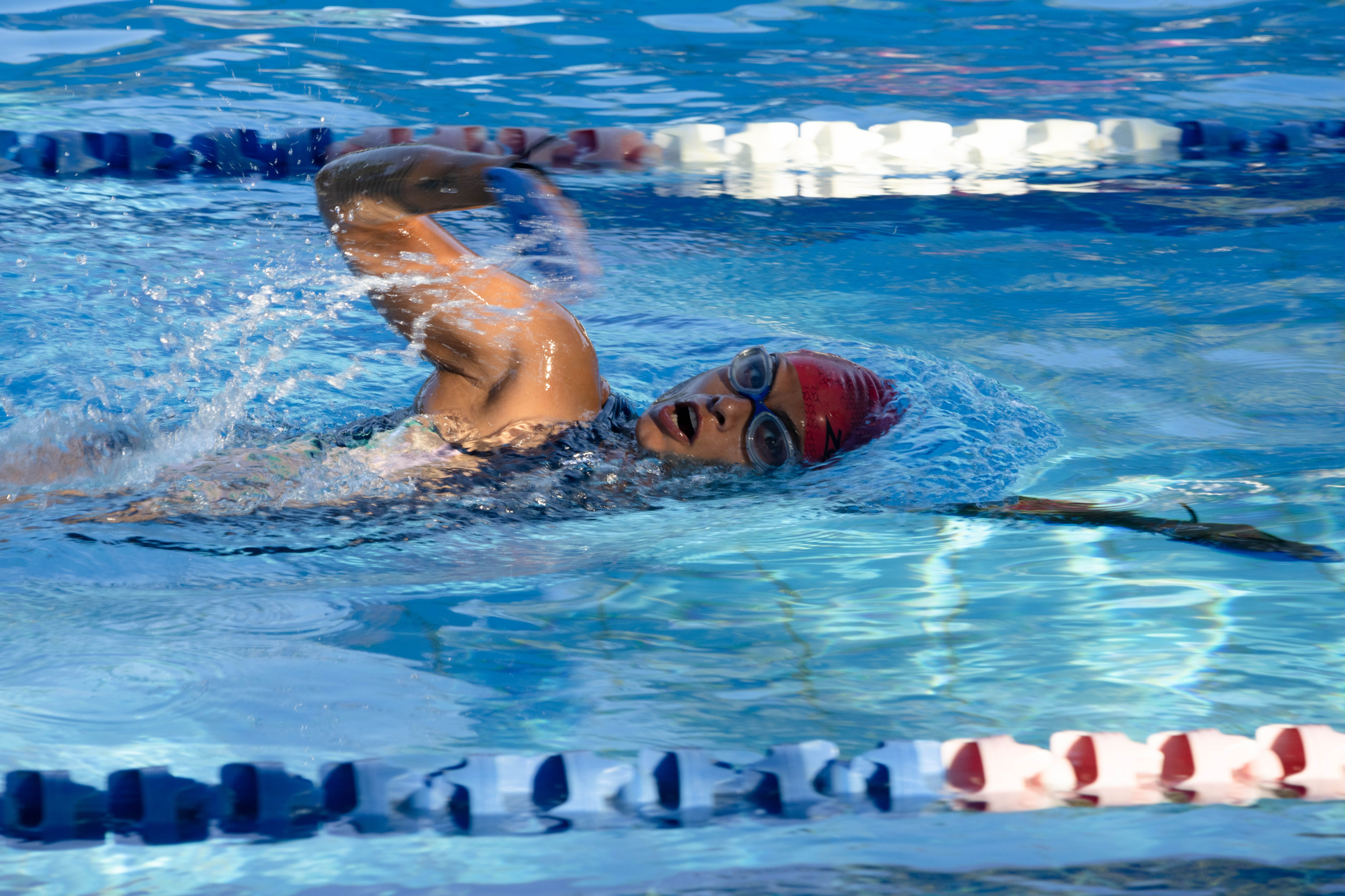 Adult swimmer doing laps in a bright, clean indoor pool facility