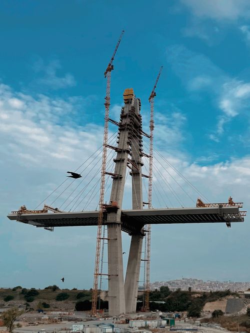 Free A cable-stayed bridge in construction with cranes against blue sky. Stock Photo