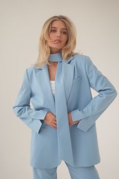 Stylish female model in a pastel blue suit posing with confidence.