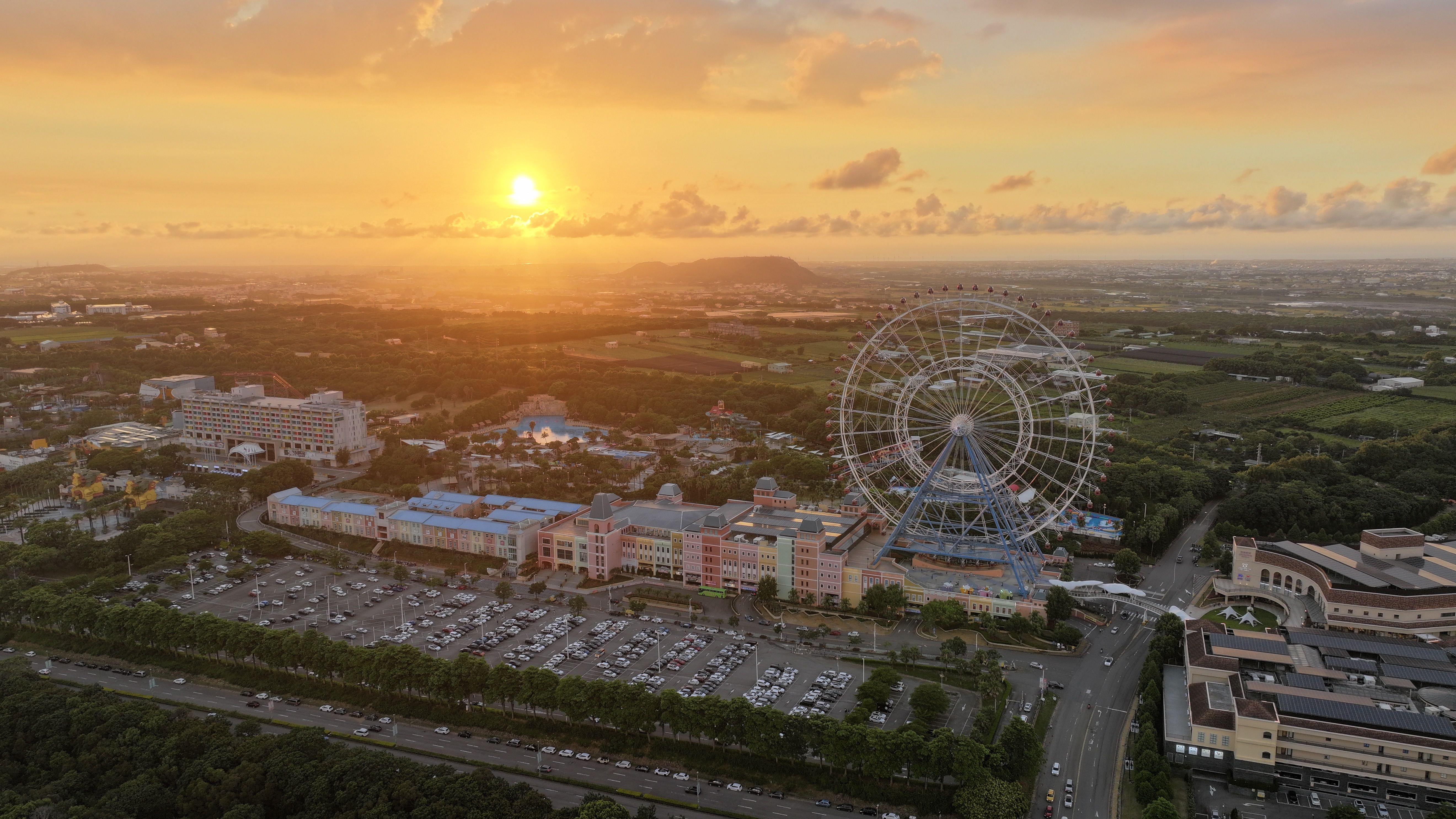 A breathtaking aerial view of a Ferris wheel and landscape at sunset in Taiwan.