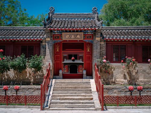 Free Entrance to a traditional Chinese temple with vibrant red details and summer greenery. Stock Photo