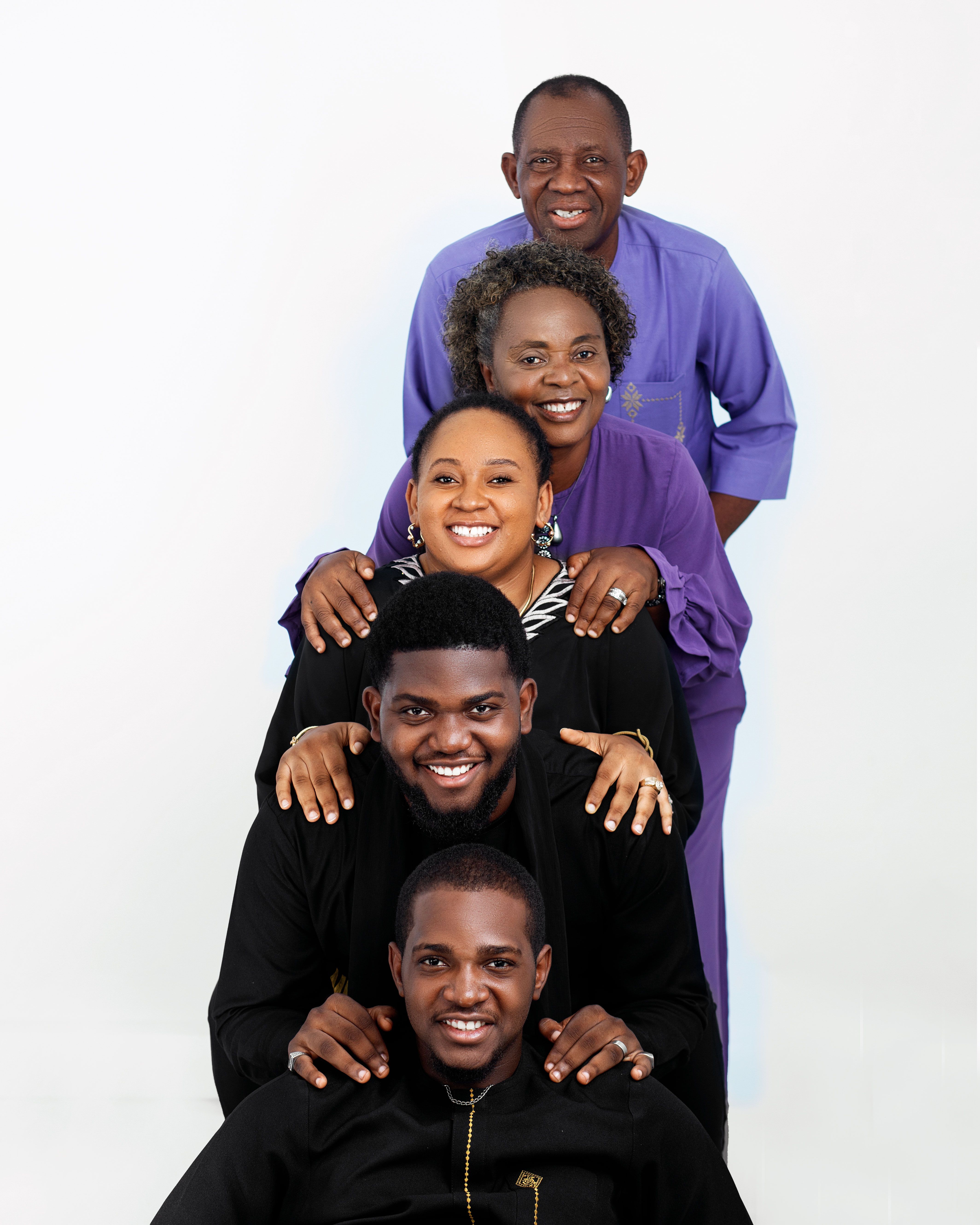 Studio portrait of a cheerful family of five posing in a vertical line.