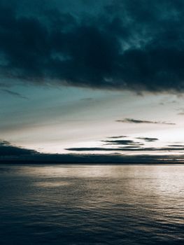 Tranquil sunset over the ocean with dramatic cloud formations creating a moody atmosphere.