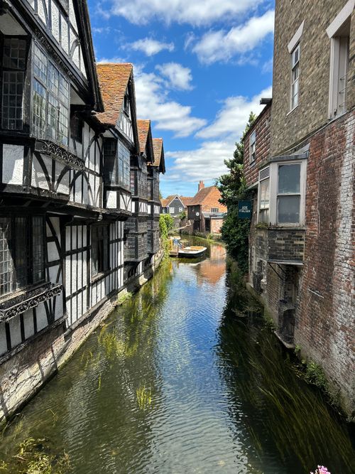 Free Picturesque canal with historic buildings in Canterbury, England, featuring vibrant summer skies. Stock Photo