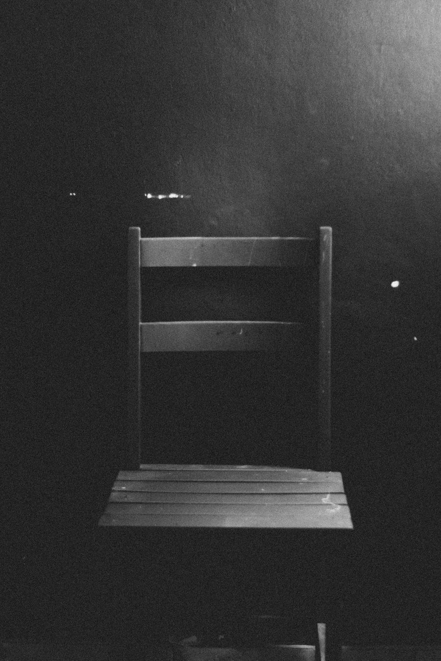 Plain wooden chair against a dark textured wall — photo by Wallace Chuck on Pexels