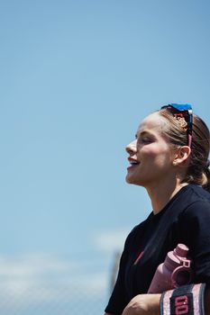 Smiling woman with sunglasses holding a water bottle outdoors on a sunny day.