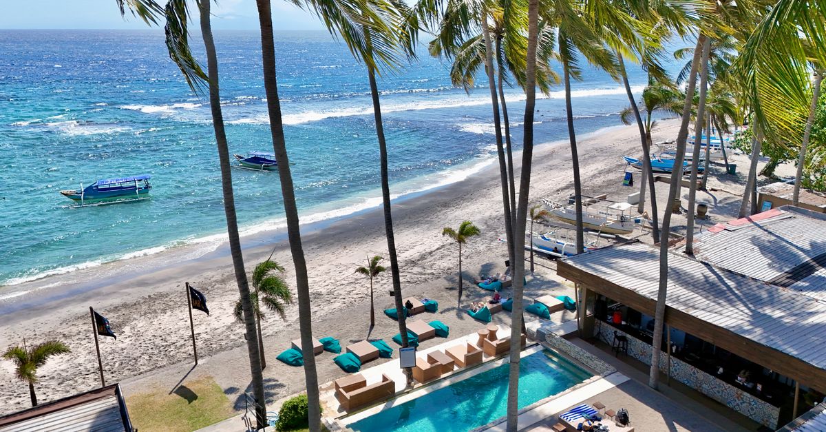 A stunning aerial view of a tropical beachfront resort with palm trees and ocean views in Bali.