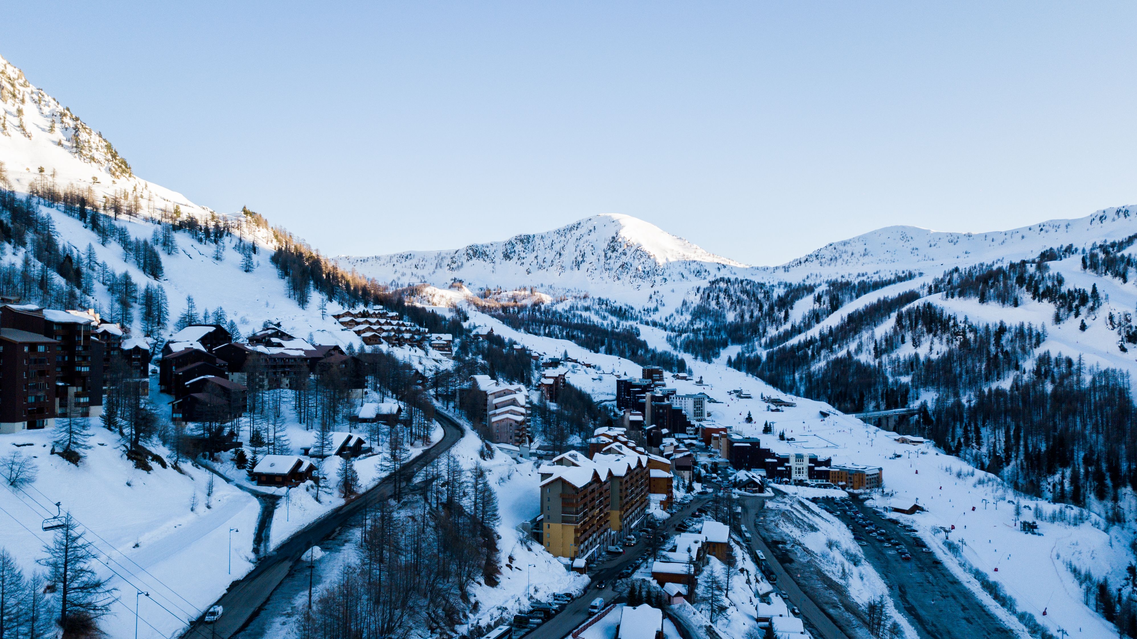 A snowy resort village spread across a high bowl with the access road curving through it