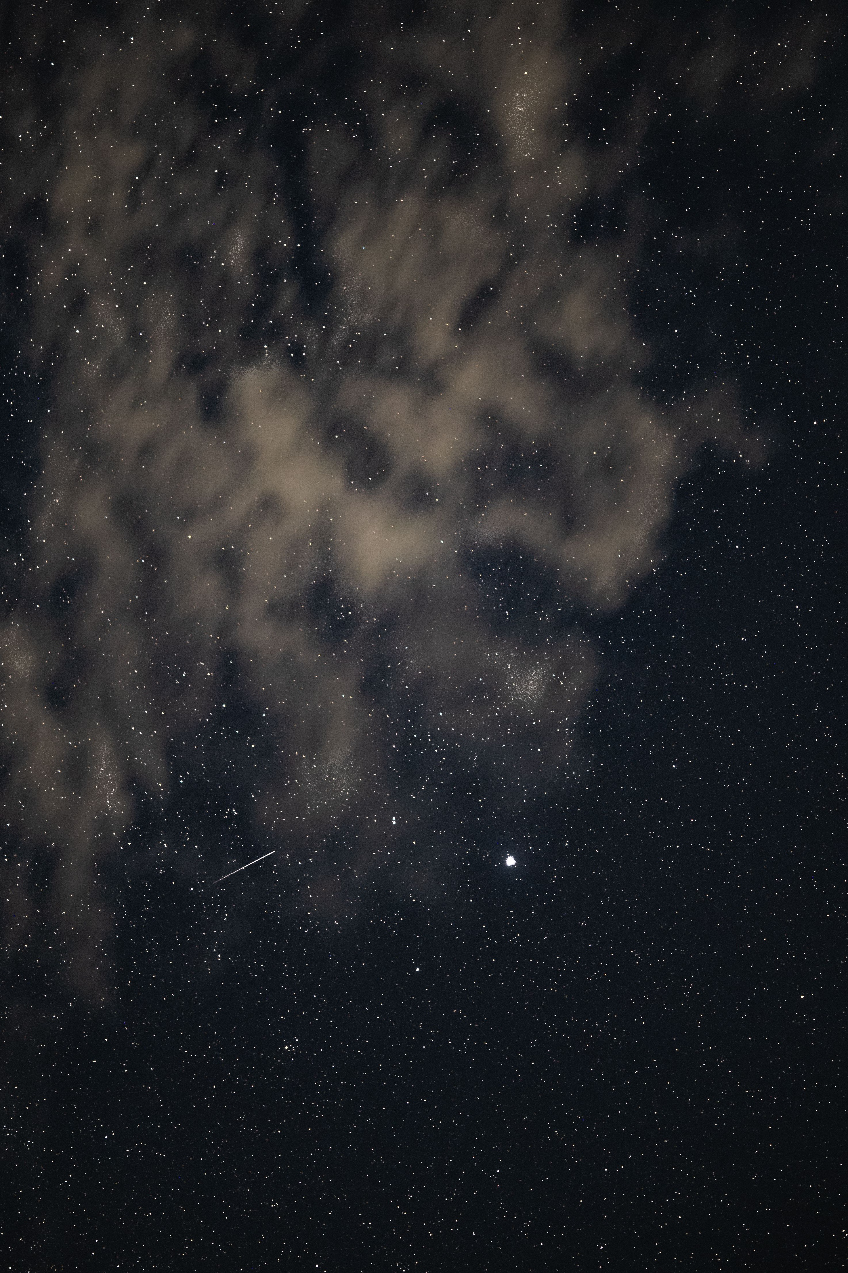 A stunning night sky filled with stars, clouds, and a visible shooting star streaking through.