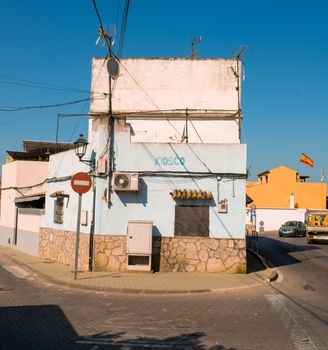 Old kiosk building with Spanish architecture on a sunny street corner.