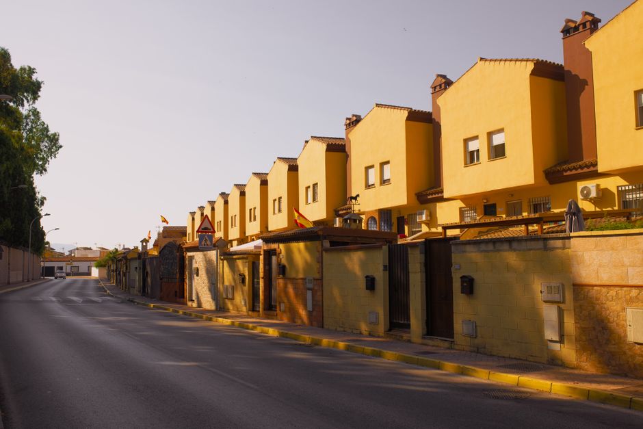 Fila de casas suburbanas amarillas bajo la cálida luz de la tarde, mostrando arquitectura mediterránea.