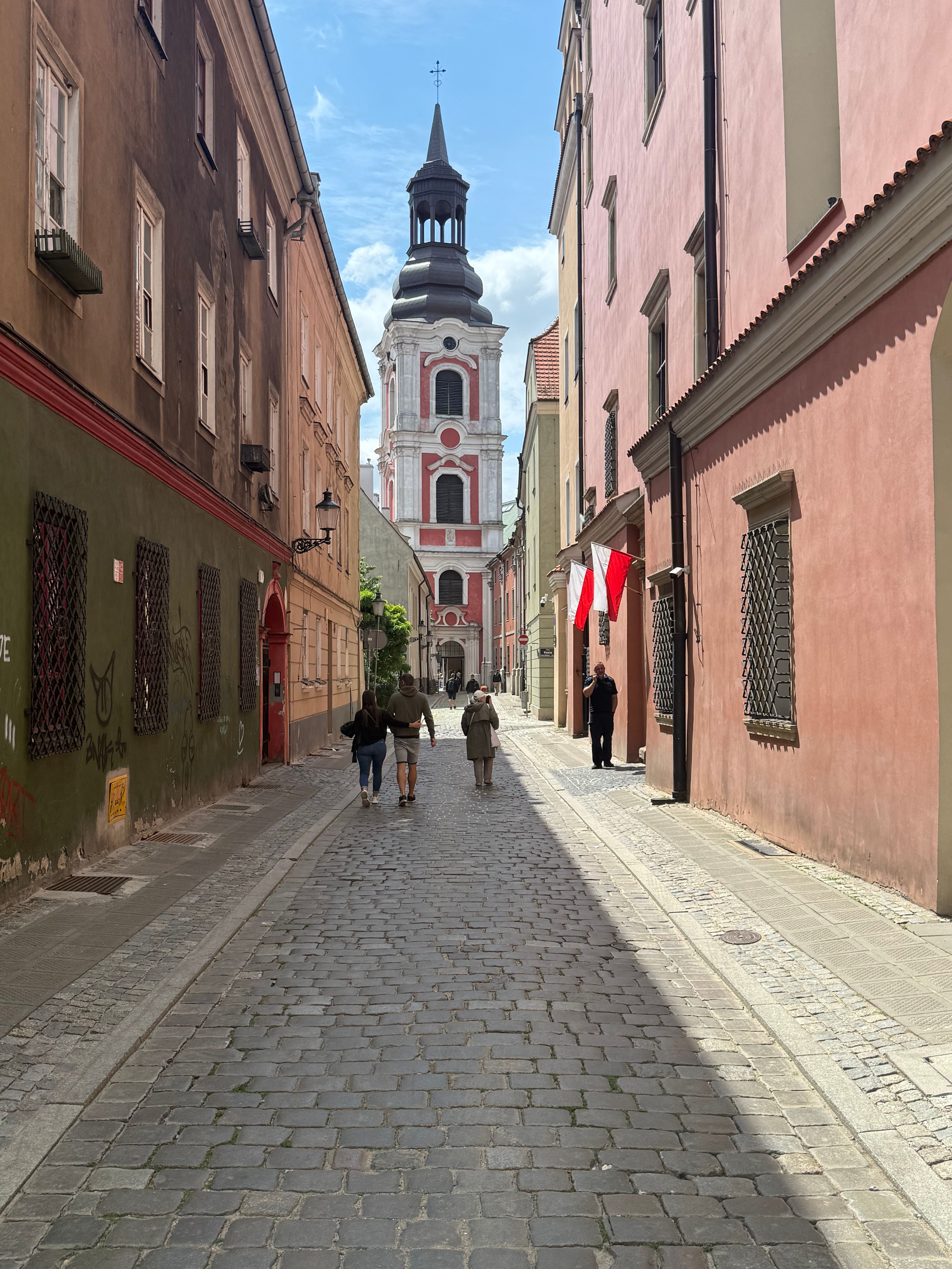 Picturesque cobblestone street leading to a historic church in a Polish town, capturing vibrant architecture.