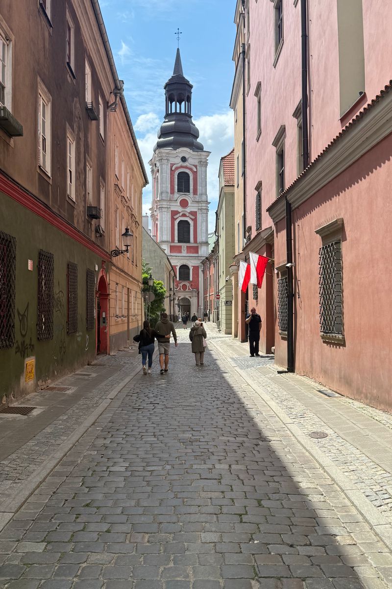 Picturesque cobblestone street leading to a historic church in a Polish town, capturing vibrant architecture.