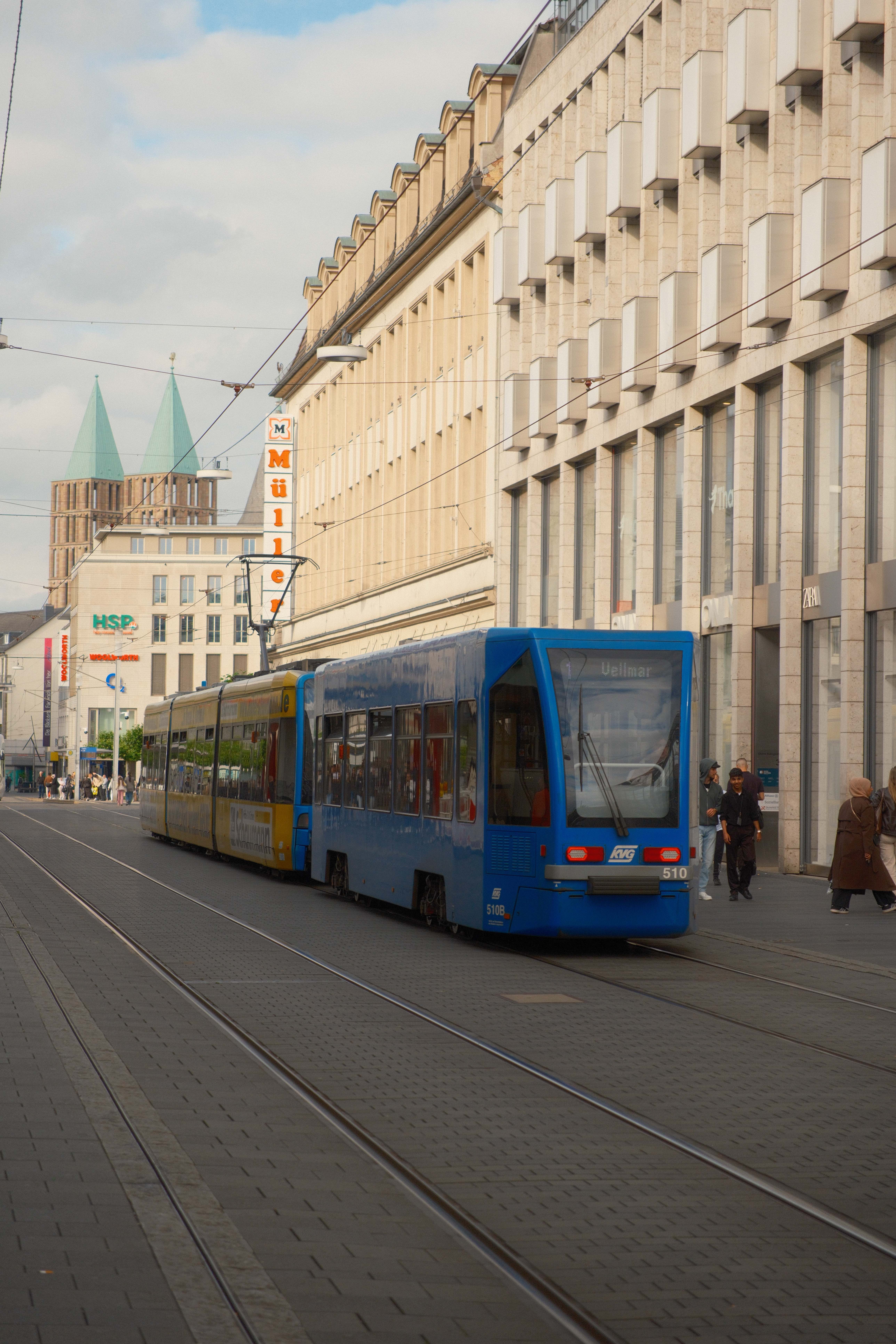 Blue urban tram moving through Kassel city center on an overcast day.
