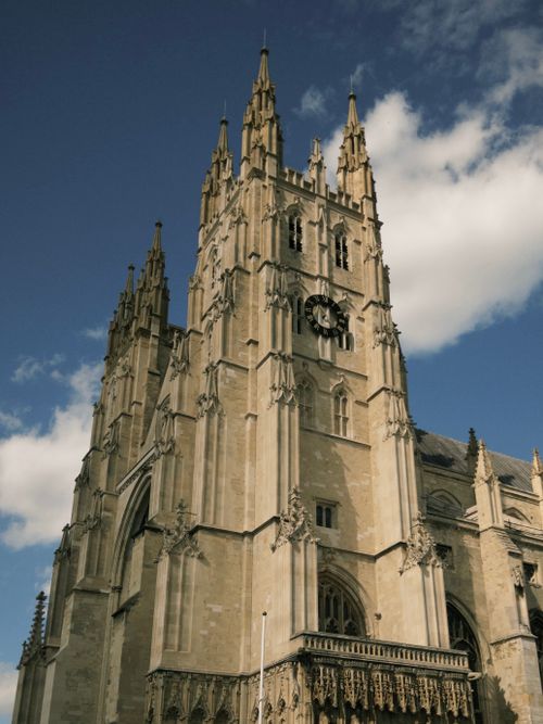 Free Dramatic upward shot of Canterbury Cathedral against a bright blue sky with clouds. Stock Photo