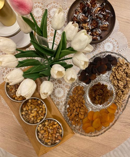 Free An elegant table setting featuring white tulips and an assortment of nuts and dried fruits on a lace cloth. Stock Photo