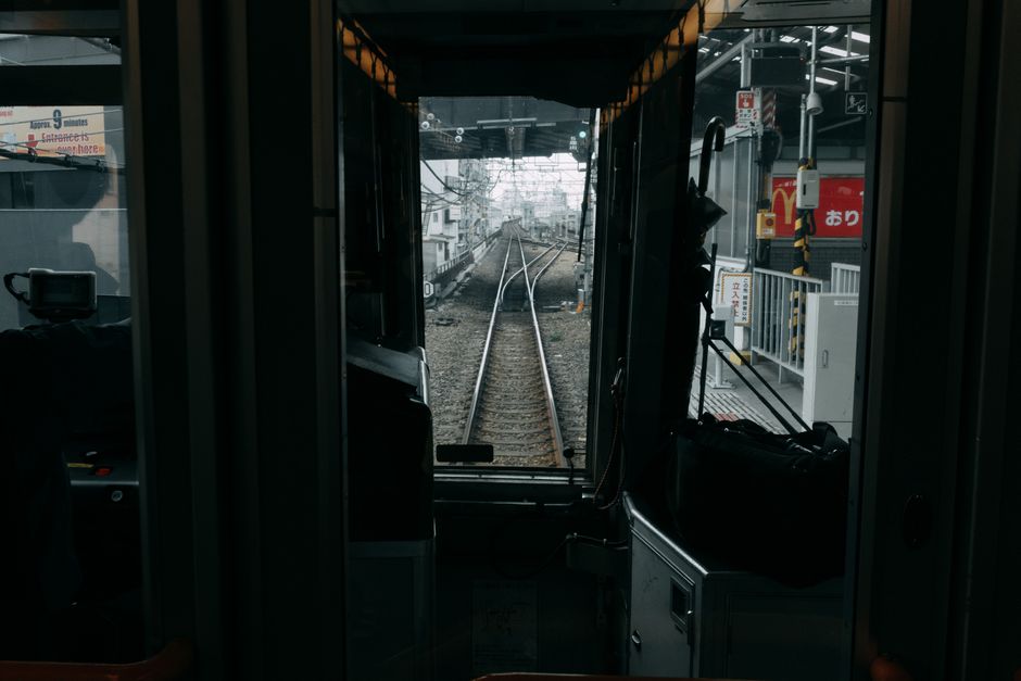 Interior view of a train cabin looking out onto railway tracks, capturing a moody urban scene.