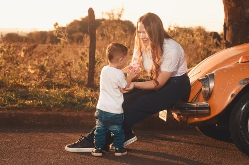 Free A warm, joyful scene of a mother and child together outdoors with a vintage car. Stock Photo