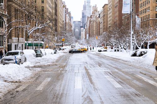 Free A snow-covered street in New York City with parked cars and people walking on a cold winter day. Stock Photo